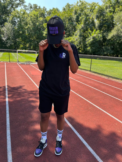 BLACK UNDERRATED TRUCKER HAT WITH PURPLE FONT